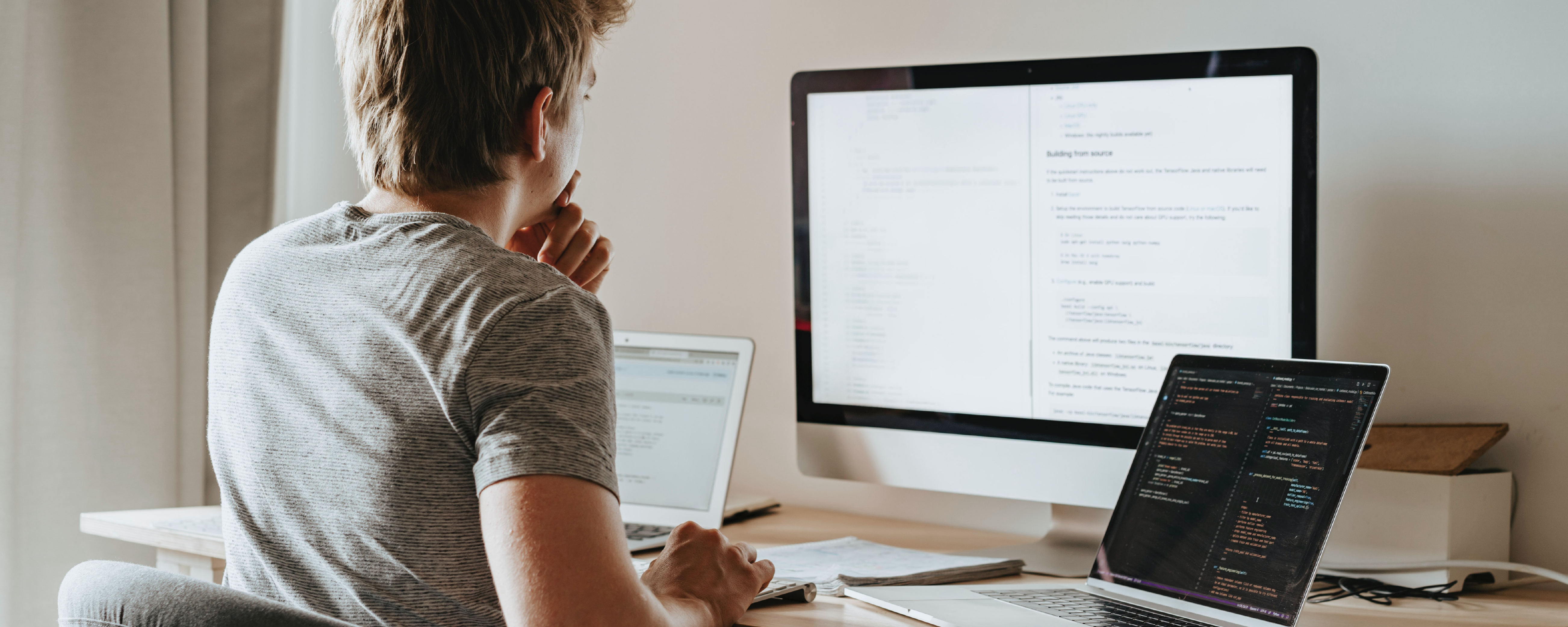 Man Sitting at Desk in Front of 3 Screens in Home Office